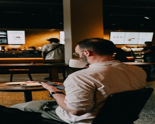 A person reviewing documents on a balanced bright mobile phone setup inside a local coffee house
